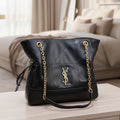 Black handbag with gold chain on a light gray background