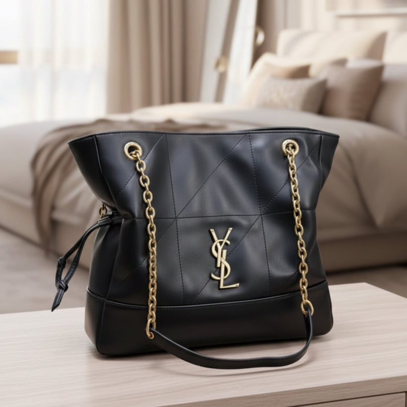 Black handbag with gold chain on a light gray background
