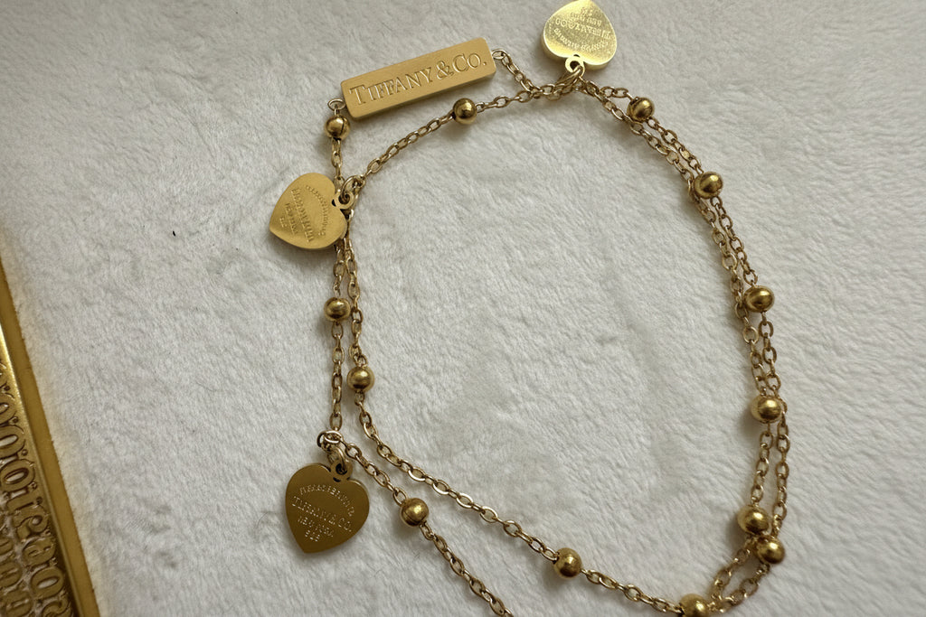 Gold double bracelet with heart-shaped charms.