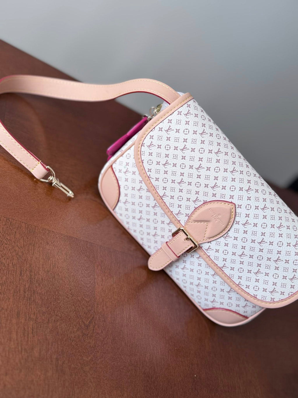 Patterned handbag with pink strap on a brown surface