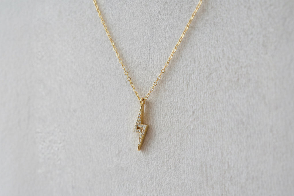Gold necklace with a small pendant on a beige background