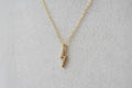 Gold necklace with a small pendant on a beige background
