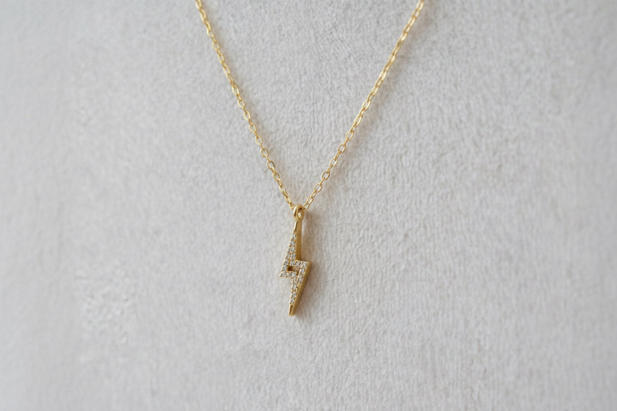 Gold necklace with a small pendant on a beige background