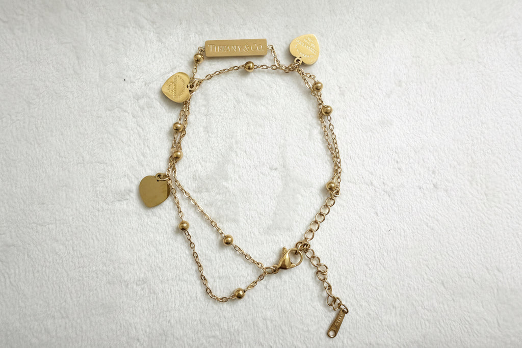 Gold double bracelet with heart-shaped charms.