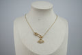 Gold necklace with a saturn/safety pin pendant