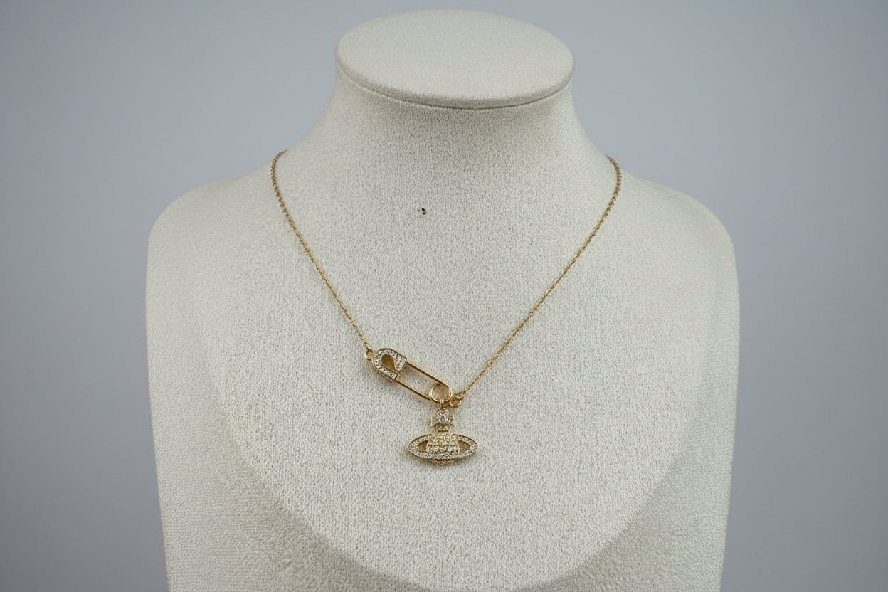 Gold necklace with a saturn/safety pin pendant