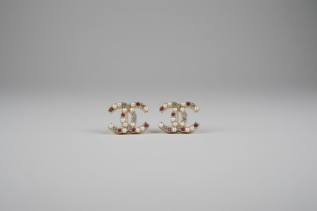 earrings on a white surface with a pink jewelry box in the background.